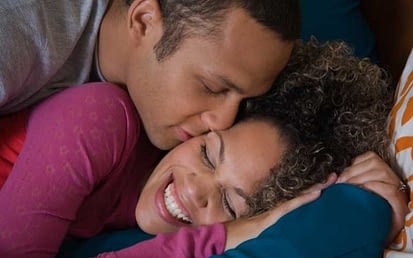 man kissing woman in bed