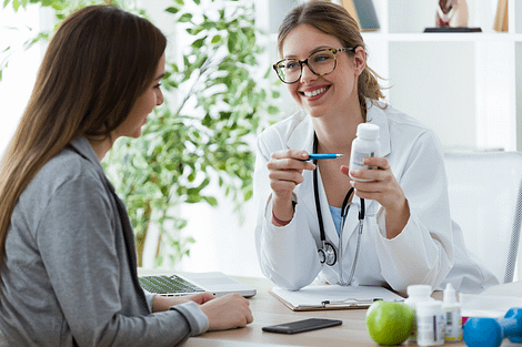 Woman talking to female doctor holding a pill bottle