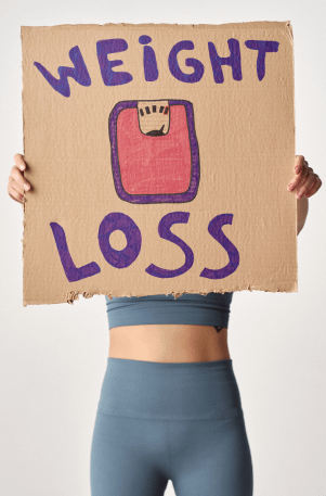 woman holding weight loss sign