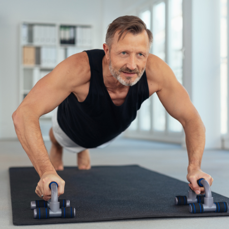 Middle-aged man exercising on handles for push-ups